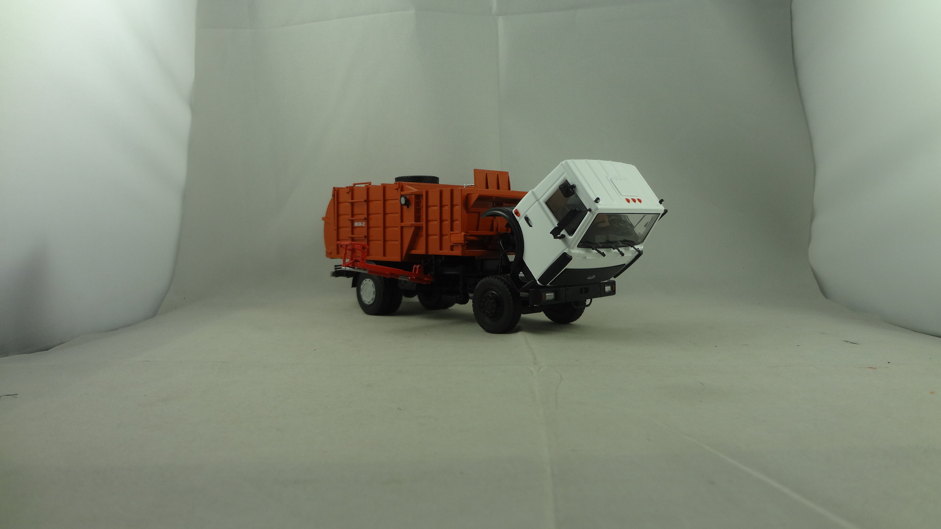 White cabine Maz truck with orange container